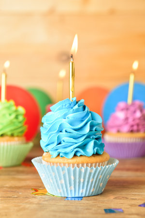 Tasty Birthday cupcakes with burning candles on wooden backgroundの写真素材