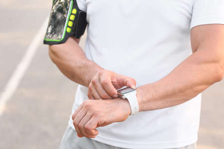 Male runner checking pulse outdoors, closeup