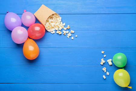 Beautiful balloons and popcorn on color wooden backgroundの写真素材