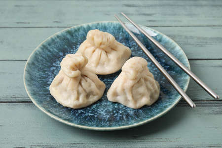 Plate with tasty dumplings and chopsticks on color wooden background, closeupの写真素材