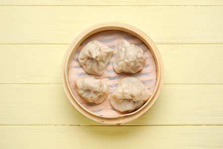 Bamboo steamer with tasty dumplings on color wooden backgroundの写真素材