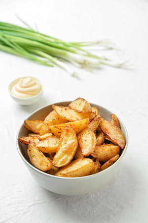 Bowl with tasty baked potato on light background