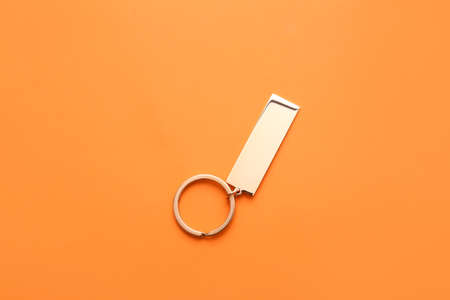Stylish metallic keychain on orange background