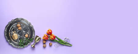 Passover Seder plate, cup and flowers on color background with space for text
