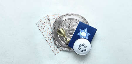 Passover Seder plate, kippah, Torah, matza and cup on light background