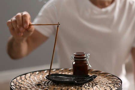 Mature man with incense sticks at home, closeupの写真素材