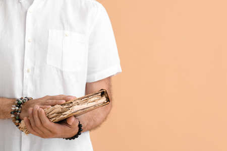 Mature man with old esoteric book on color background