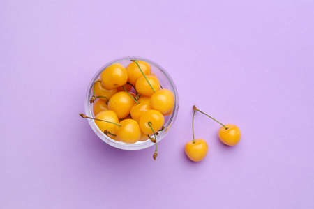 Bowl with tasty sweet cherries on color background
