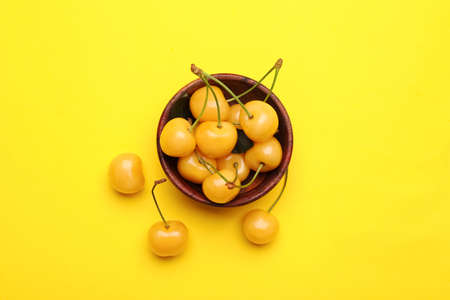 Bowl with tasty sweet cherries on color background