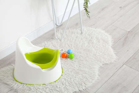 Potty and rattle on gray wooden floor near white wall