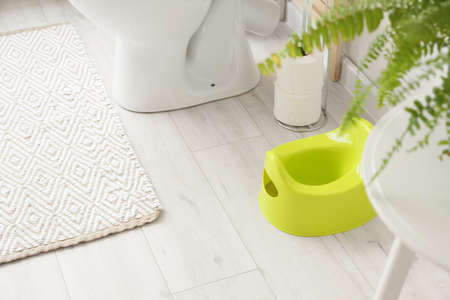 Green potty on light wooden floor in restroomの写真素材