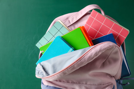 School backpack and stationery near blackboard