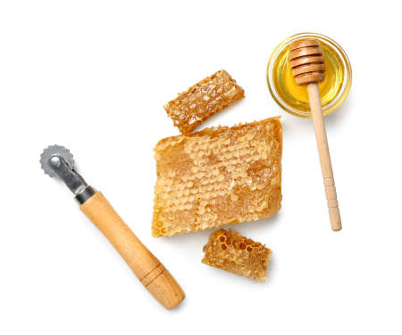 Bee knife with honey on white backgroundの写真素材
