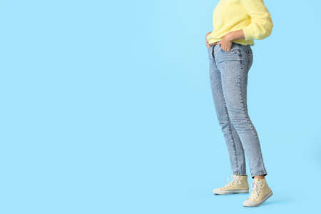 Fashionable young woman in stylish jeans on color backgroundの写真素材