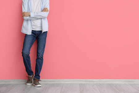 Fashionable young man in stylish jeans near color wallの写真素材