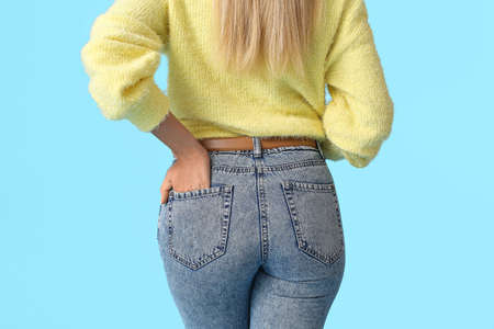 Fashionable young woman in stylish jeans on color backgroundの写真素材
