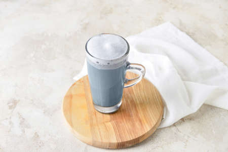 Wooden board with glass cup of Charcoal Latte on light tableの写真素材
