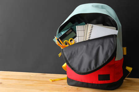 School backpack and stationery on table near blackboard