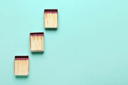 Boxes with whole wooden matchsticks on color background