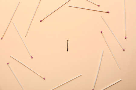 Burnt match among whole ones on color background. concept of uniqueness