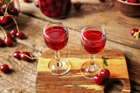 Glasses of sweet cherry wine on wooden backgroundの写真素材