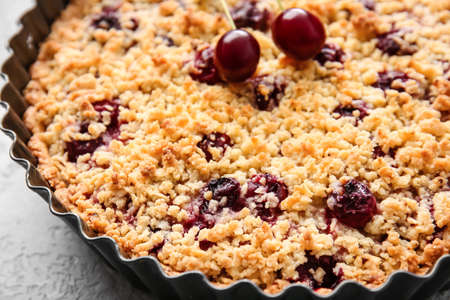 Baking dish with tasty cherry pie on light background, closeup