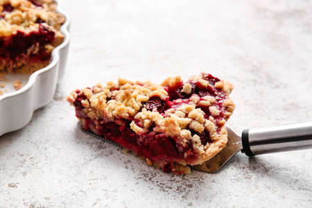 Spatula with piece of tasty cherry pie on light background, closeup