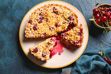 Plate with tasty cherry pie on color background