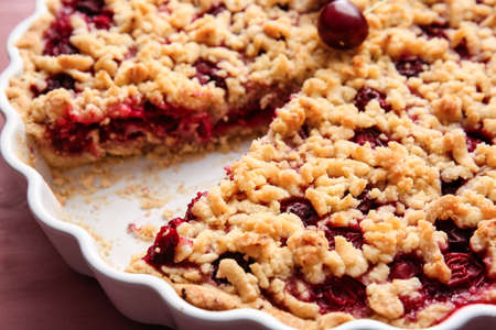 Baking dish with tasty cherry pie on color background, closeup