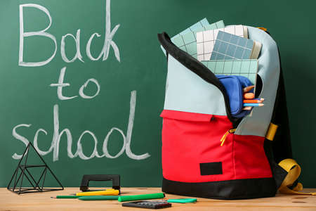 School backpack, stationery and decor on table in classroom