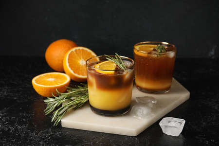 Glasses of tasty coffee with orange juice on dark background