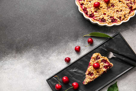 Plate with piece of tasty cherry pie on black and white background