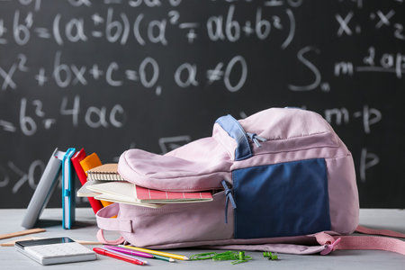 School backpack with stationery in classroom