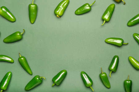 Frame made of green jalapeno peppers on color background
