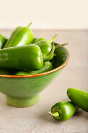 Bowl with green jalapeno peppers on light background, closeup