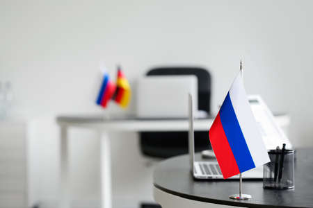 Russian flag, stationery holder and laptop on table in officeの写真素材