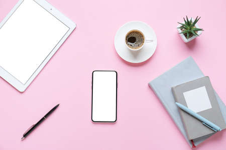 Mobile phone, tablet computer, cup of coffee and stationery on color backgroundの写真素材
