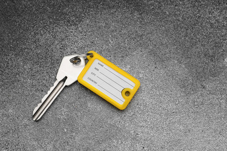 Key with yellow plastic tag on grunge background