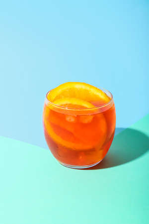 Glass of Aperol spritz cocktail on color backgroundの写真素材