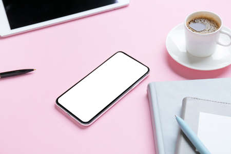 Mobile phone and cup of coffee on color background, closeup