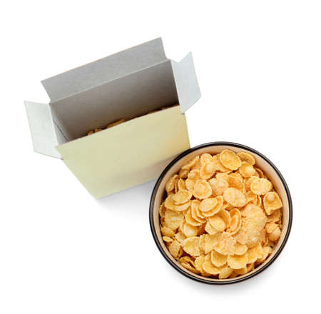 Bowl with tasty cornflakes and paper box on white background