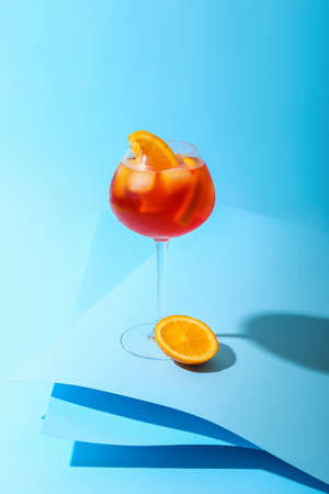 Glass of Aperol spritz cocktail on color backgroundの写真素材