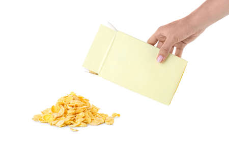 Woman pouring tasty cornflakes from paper box tasty cornflakes on white background
