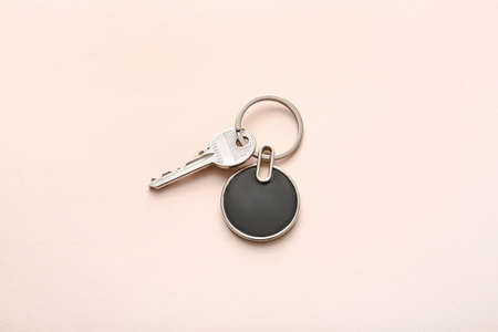 Key with stylish keychain on light background