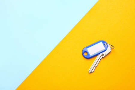 Plastic tag with key on color background
