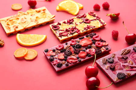 Handmade chocolate bars with fruits, berries and nuts on color backgroundの写真素材