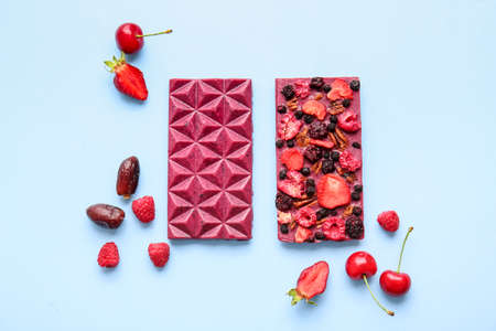 Handmade chocolate bars with fruits, berries and nuts on color background