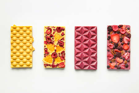 Handmade chocolate bars with fruits, berries and nuts on white background