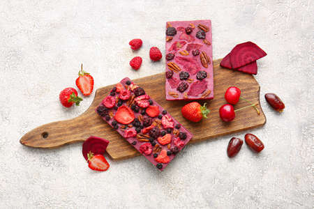 Handmade chocolate bars with fruits, berries and nuts on light background
