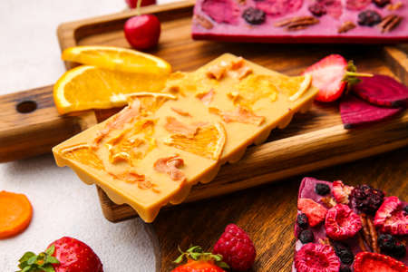Handmade chocolate bars with fruits and berries on light background, closeup